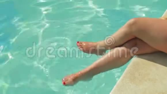 女性的腿垂到游泳池里搅拌视频的预览图