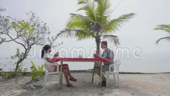 跨种族夫妇在海边的热带度假胜地的咖啡馆喝茶点视频的预览图