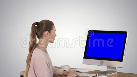 女孩坐在电脑显示器前看着一些微笑的蓝色屏幕模拟显示梯度视频的预览图