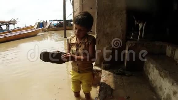小印度男孩用双手把他的拖鞋从泥淹没的圣恒河中清除背景是码头上的脏水奶牛和船只视频的预览图
