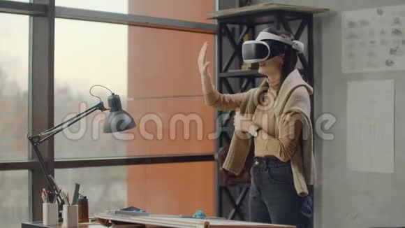办公室里的现代女工程师设计人员戴着一个虚拟现实头盔戴着一个大窗户视频的预览图