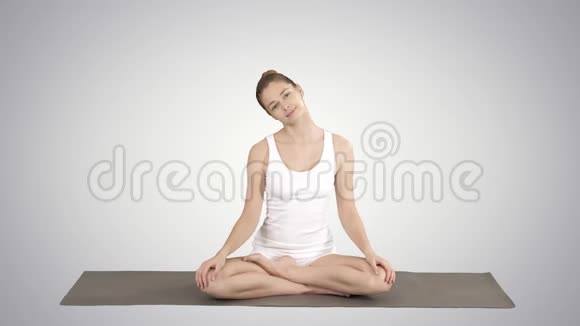 平静的女人练习瑜伽坐在莲花的姿势伸展颈部的梯度背景视频的预览图