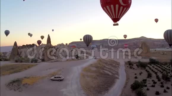 迷人的空中全景观看巨大的热气球高飞在傍晚日落天空上的岩石沙石沙漠视频的预览图