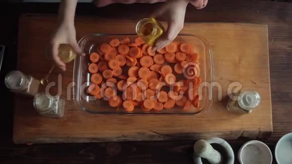 一个年轻的女孩把香料放在一个碗里用切碎的胡萝卜在厨房里做饭特写镜头从上面看视频的预览图