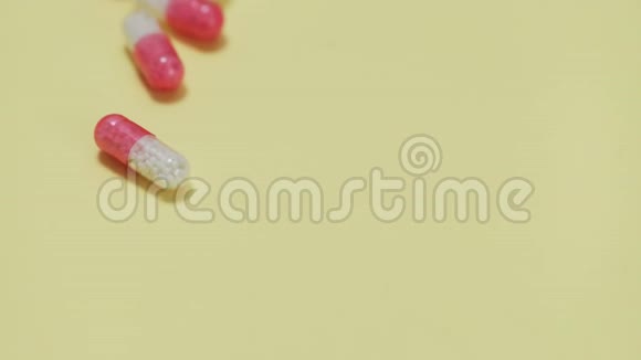 粉红色和白色药片黄色背景的瓶子视频的预览图