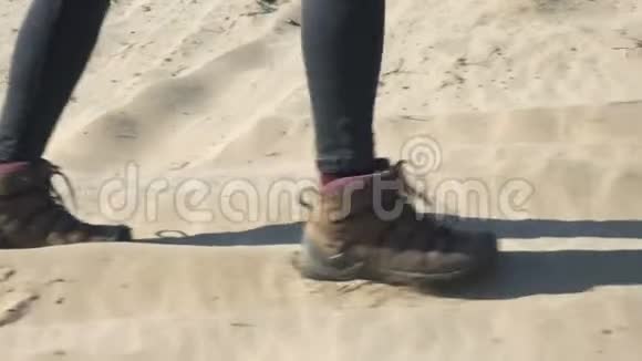 女人的脚和女徒步旅行者的鞋子在沙滩上行走视频的预览图