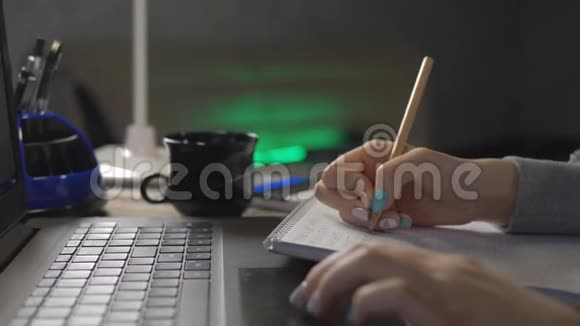 一个十几岁的女孩在笔记本显示器前做作业在笔记本上写铅笔的女孩视频的预览图
