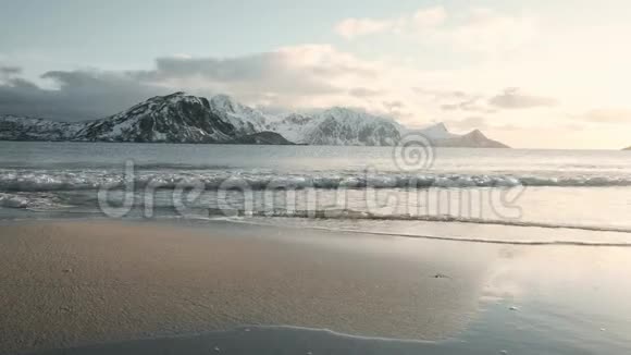 波浪慢慢地冲刷着一个叫做豪克兰的沙滩日落时非常平静的气氛雪景和群山在后面视频的预览图