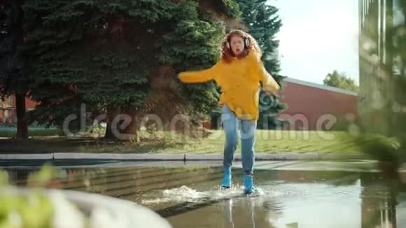 快乐的少年穿着雨衣在水坑里跳着享受音乐视频的预览图