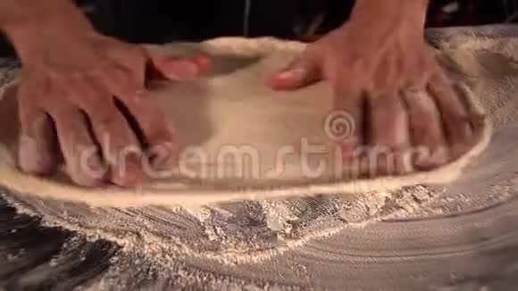 比萨饼师男子手捏比萨饼面团光滑的圆形运动拉伸面团视频的预览图