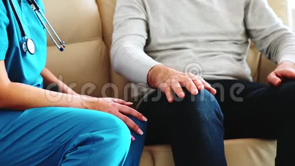 一位女护士坐在沙发上用一只老人的手拍着她的近镜头视频的预览图