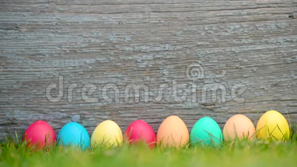 五颜六色的复活节彩蛋在一片草地上排成一排背景是木制的视频的预览图