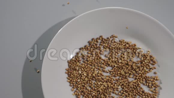 荞麦颗粒掉进白色的碗里顶部视图慢速运动视频的预览图