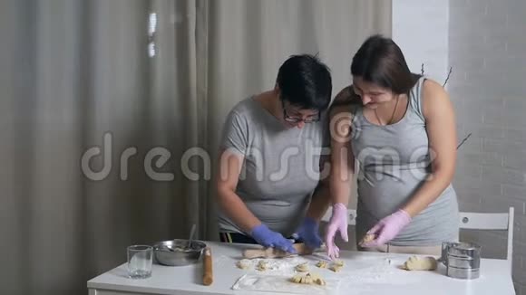 妈妈和女儿在家厨房准备饺子和糕点的面团视频的预览图