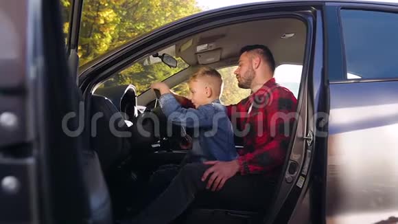 坐在前排座位上和他的好儿子一起教开车的英俊留胡子男人的侧视图视频的预览图