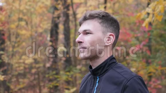 男性自行车手健康的年轻职业运动员在秋季公园训练前戴上黑色自行车头盔动机视频的预览图