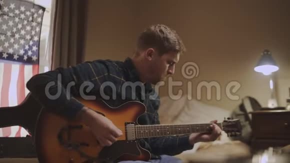 充满激情的年轻人坐在床上晚上练习弹吉他视频的预览图