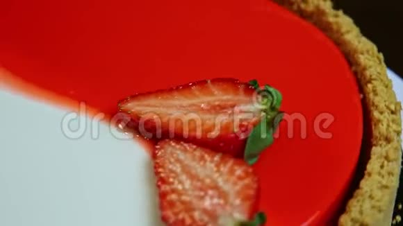 带有草莓切片装饰的上光芝士蛋糕旋转着视频的预览图