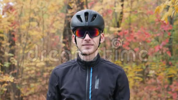 秋季公园年轻职业男性自行车运动员肖像迷人的微笑活泼的家伙摘下黑色头盔和眼镜视频的预览图
