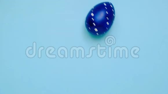 复活节彩蛋滚滚互相敲着蓝桌子鸡蛋时髦的彩色经典蓝色白色和金色快乐视频的预览图