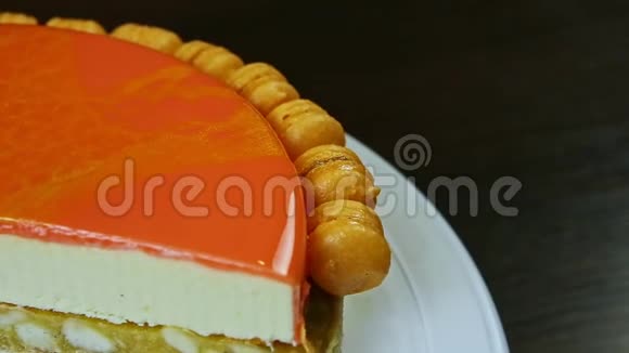 顶部的特写一半的橙色釉面芝士蛋糕旋转在白色旋转架上视频的预览图