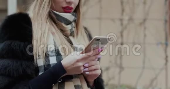 城市里使用智能手机的年轻女人女生使用手机拍照APP灯光背景技术冬季视频的预览图