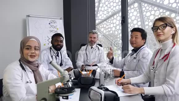 迷人的微笑高技能医生团队在医院办公室的摄像机上摆姿势并显示签名OK视频的预览图