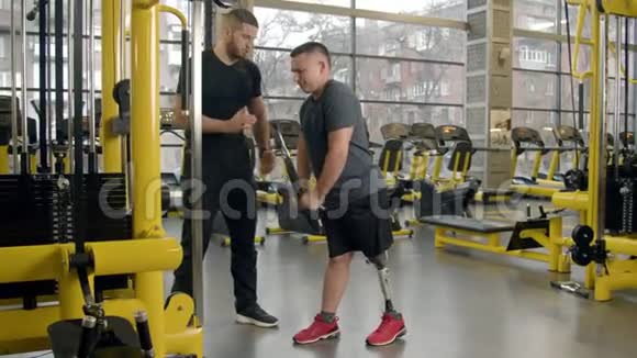 残疾青年在健身房的教练的帮助下健身视频的预览图