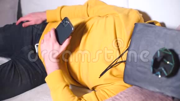 一个戴着黑色面具手里拿着智能手机的男人在沙发上醒来视频的预览图