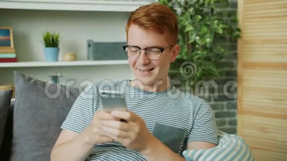 快乐的年轻人在家里用智能手机记录微笑的语音信息视频的预览图