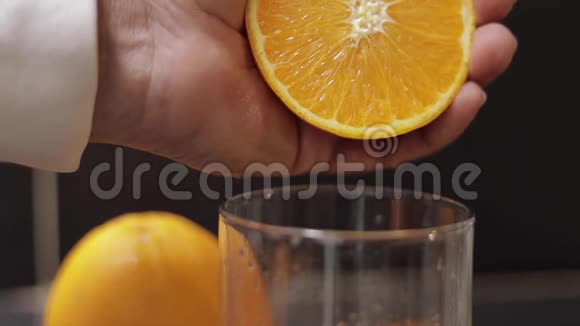 男人的手把橘子汁挤到玻璃杯里男人手里拿着一半的橘子视频的预览图