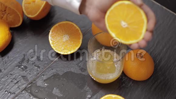 男人的手把橘子汁挤到玻璃杯里男人手里拿着一半的橘子视频的预览图