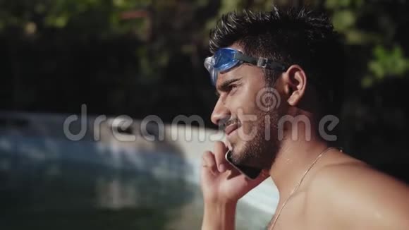 特写镜头穿着裸托索的印度男人在泳池里站着潜水后打电话视频的预览图