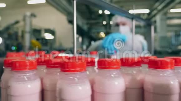 工厂工人从传送带上拿着酸奶的瓶子视频的预览图