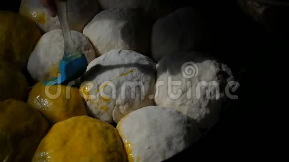 自制烘焙片上一个女面包师用蛋黄将面团中的小球涂上油脂特别厨房视频的预览图