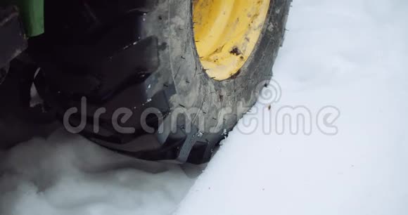 在刚刚落下的雪中慢慢滚动的拖拉机轮胎视频的预览图