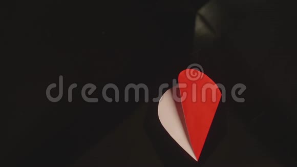 女孩手拿着一颗红色的纸心里面写着字用黑色背景关闭视图视频的预览图