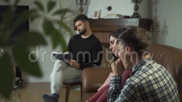 疲惫的高加索家庭坐在前台打哈欠心理学家在后台做笔记年轻人视频的预览图