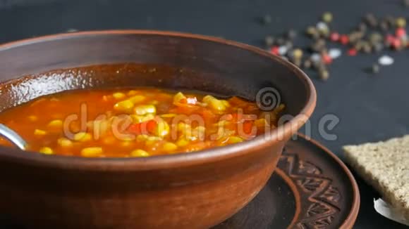 热的红番茄汤配玉米用汤匙放在一个棕色的土制盘子里视频的预览图