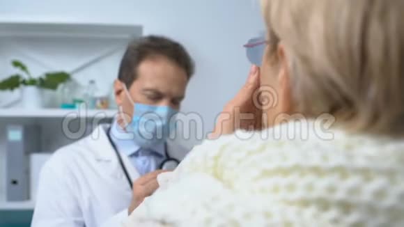 戴围巾的老妇人打喷嚏医生用口罩填写病历症状视频的预览图