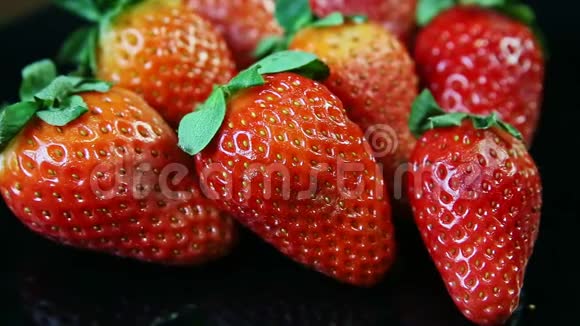 整个新鲜多汁的红色草莓的宏观景观群躺在黑色背景上视频的预览图