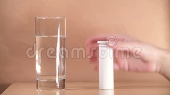 在床头柜上特写一个玻璃杯其中一个女孩扔了一颗药丸视频的预览图