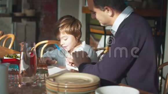 父亲和儿子在咖啡馆玩抽搐战术视频的预览图