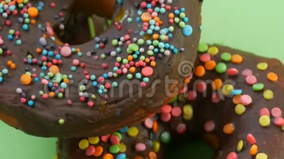 美国甜甜圈五颜六色的釉和粉末在绿色背景上旋转近距离观看视频的预览图