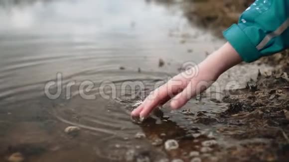 一个男孩触摸河岸附近的脏水春季洪水一个孩子走在街上视频的预览图