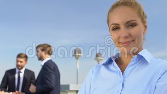 快乐的商务女士在镜头前微笑同事在后台聊天职业生涯视频的预览图