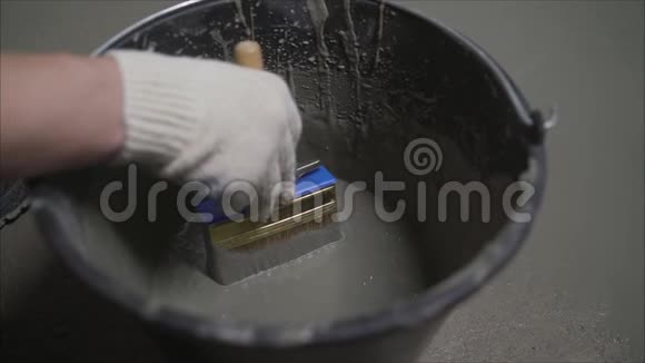 手拌防水砂浆一桶男性手拿刷子在地板上涂上防水防水解决方案视频的预览图