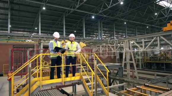 两个人在一家砖厂工作检查机器工厂设施的专业工厂工人视频的预览图