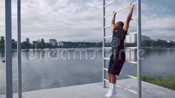 强壮的非洲男人通过把腿抬高到水平来做腹肌视频的预览图