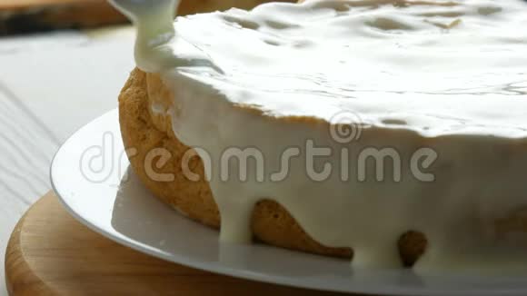 关闭视野女人在烤好的面团上撒奶油女性手在蛋糕上用勺子倒白色奶油视频的预览图